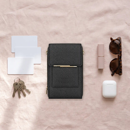 Bolso negro rodeado de lo que cabe: tarjetas, llaves, labial, gafas y estuche de audífonos