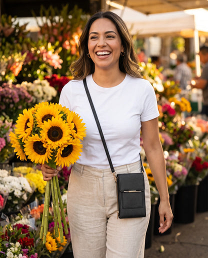 Mujer sonriente con flores en un mercado y el bolso negro cruzado