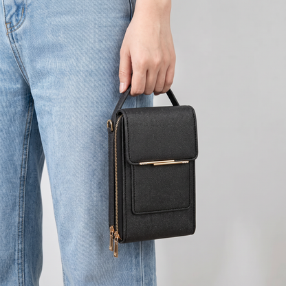 Bolso negro sostenido en la mano junto al jean para ver su tamaño compacto